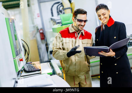 Pretty young woman controlling process in the factory with male worker Stock Photo