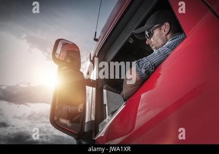 Red Semi Truck. Caucasian Truck Driver Preparing For the Next Destination. Stock Photo