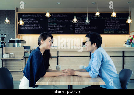 Dating in a cafe. Beautiful Asian lover couple sitting in a cafe enjoying in coffee and conversation. Love and romance. Stock Photo