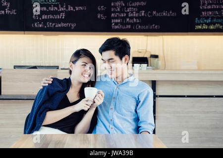 Dating in a cafe. Beautiful Asian lover couple sitting in a cafe enjoying in coffee and conversation. Love and romance. Stock Photo