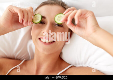 beautiful woman applying cucumbers to eyes at home Stock Photo