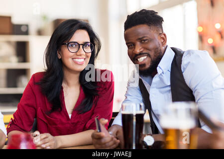 happy man and woman with smartphone at bar Stock Photo