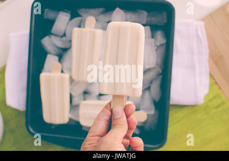 Vanilla ice cream Popsicles melting over tray of ice on summer day.  View looking down from above. Stock Photo