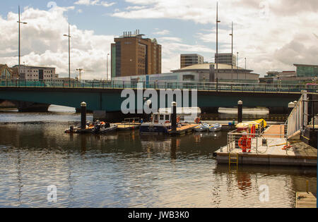 Small boats on their moorings at The Queen Elizabeth 2 bridge across the  River Lagan at the Donegall Quay in the harbour in Belfast Northern Ireland Stock Photo