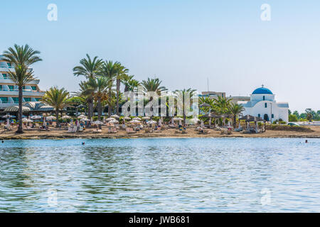 Paphos, Cyprus - September 20, 2016: View of the beautiful beach in Paphos, Cyprus. A fragment of the Mediterranean Sea and a small white Orthodox chu Stock Photo
