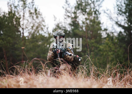 HUMALA, ESTONIA - 09 APR 2016: Soldier in camouflage with weapon protect his position. Military tactical airsoft game. Stock Photo