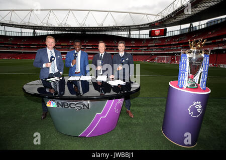 The Premier League trophy on display and the NBC Sports tv presenting team of (left-right) Arlo White, Robbie Earle, Lee Dixon and Kyle Martino before the Premier League match at The Emirates Stadium, London. Stock Photo