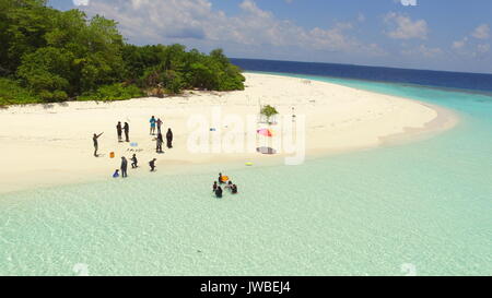 Maldivian uninhabited island with white sandy beach while a family have a picnic in coral islands beach Stock Photo