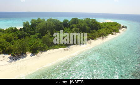 Maldivian uninhabited island with white sandy beach while a family have a picnic in coral islands beach Stock Photo