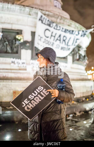 a woman holding a sign je suis charlie, standing out in front of the statue place de la republique. Homage at the victims of Charlie hebdo killing in  Stock Photo