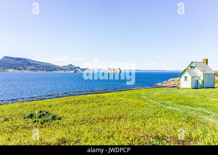 View of Rocher Perce from Bonaventure Island with ocean and house Stock Photo