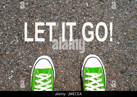Feet concept with green sneakers on black background with let it go text. Stock Photo