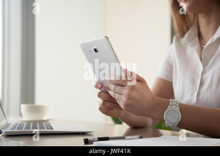 Female hands holding digital tablet at work desk, close up Stock Photo