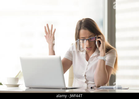 Disgruntled angry businesswoman arguing on cell phone sitting at Stock Photo