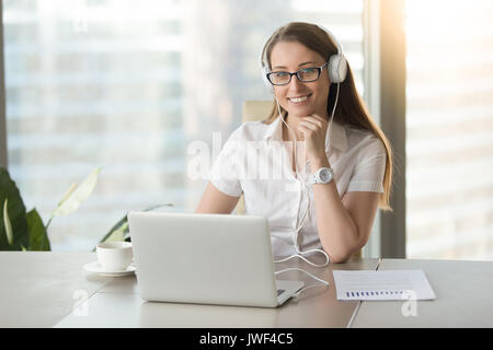 Smiling businesswoman wearing headphones with laptop posing at w Stock Photo
