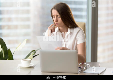 Concentrated focused businesswoman analyzing document, holding f Stock Photo