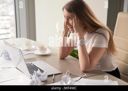 Hysterical woman experiencing burnout, screaming at workplace, o Stock Photo