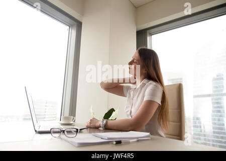 Tired businesswoman feeling neck pain after long work on compute Stock Photo