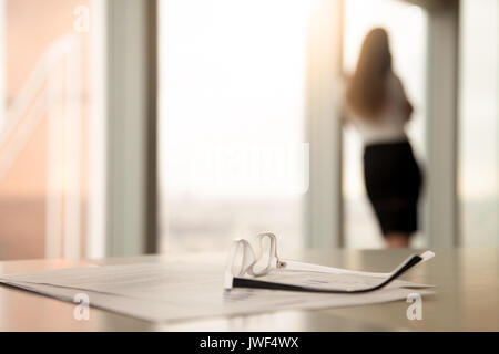Corrective glasses for reading on desk, female silhouette at bac Stock Photo