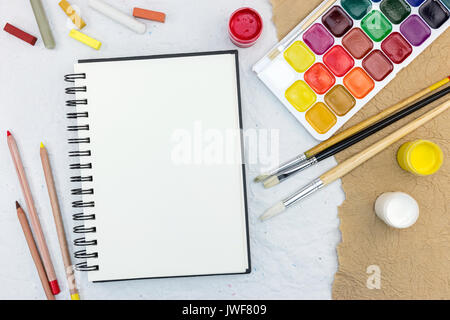 artist work tools on table: watercolor, paintbrushes and pencils with chalks. creative workplace. Stock Photo