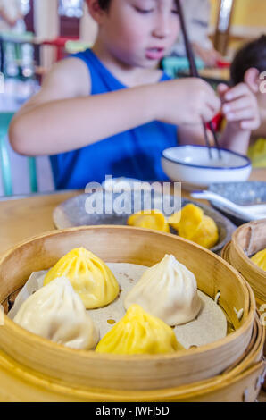 A young boy eats Chinese soup dumplings in Shanghai. Stock Photo