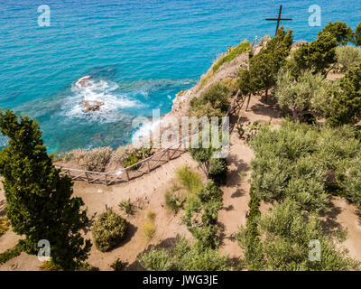 Aerial view of a cross on the promontory of the Sanctuary of Santa Maria dell'isola, Tropea, Calabria, Italy. Gardens of the sanctuary. Sea and waves Stock Photo