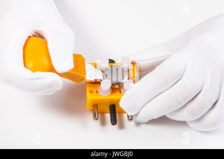 watchmaker workshop - opening back cover of watch for replacing battery by yellow opener on white background Stock Photo