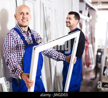 Two positive workmen inspecting PVC manufacturing output in workshop Stock Photo