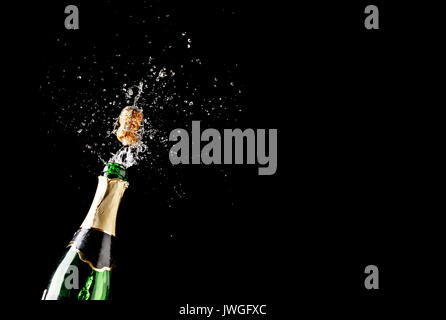 Cork flies out of champagne bottle isolated on black background Stock Photo
