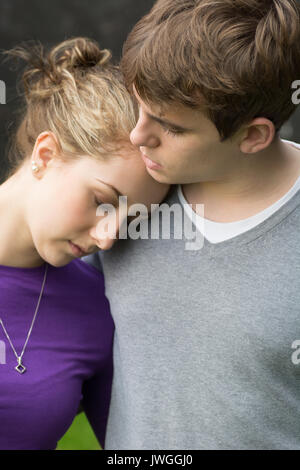 Sad young woman leaning on her boyfriend outdoors Stock Photo