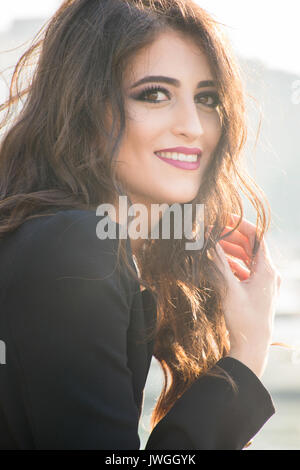 Beautiful young woman hand touching hair smiling outdoors Stock Photo