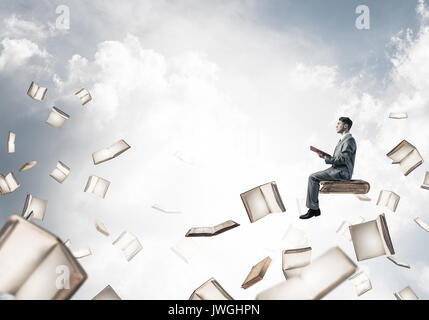 Man reading book and many of them flying in air Stock Photo