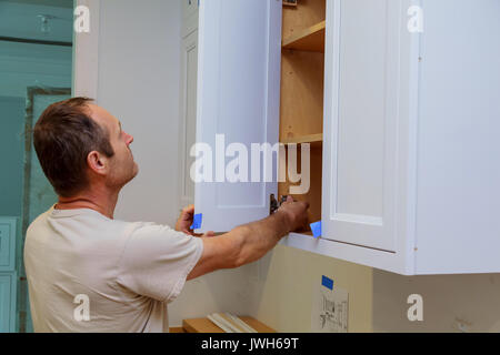 Installation of kitchen. Worker installs doors to kitchen cabinet. Stock Photo