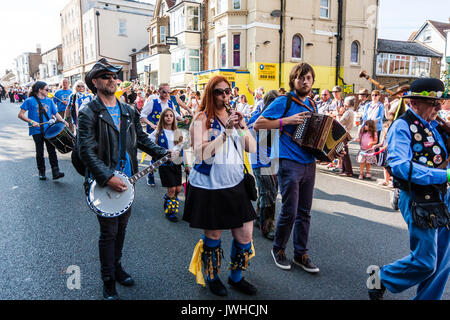 Broadstairs Folk Week Festival parade. Musicians from the Royal Liberty Morris folk dancers marching in the High Street. One plays bagpipes, one accordion, one flute and another playing the banjo. Stock Photo
