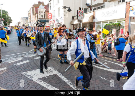Broadstairs Folk Week Festival parade. Musicians from the Royal Liberty Morris folk dancers marching in the High Street. One plays bagpipes, one flute and another playing the banjo. Stock Photo