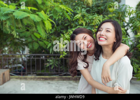 Asian sisters hugging and smiling in the park. Stock Photo