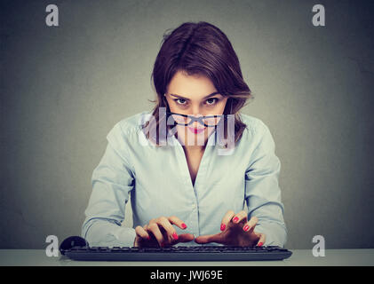 Crazy looking nerdy woman typing on the keyboard wondering what to reply Stock Photo