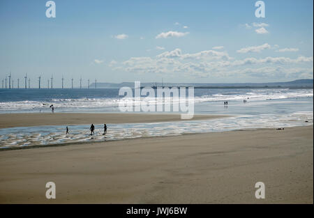 Summer Holidaymakers on the Beach at Seaton Carew Hartlepool England with an offshore wind turbine farm in the sea Stock Photo