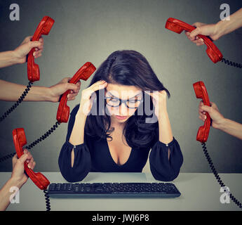 Tired stressed business woman working on computer overwhelmed by too many phone calls in her office Stock Photo