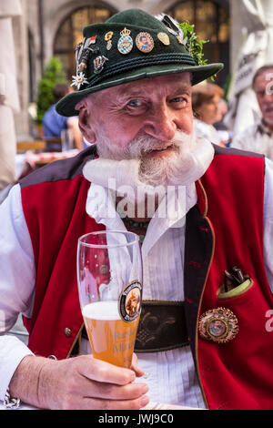 Typical Bavarian character in traditional costume of lederhosen, waistcoat, hat  with enamel badges, jewellery, and displaying extravagant beards and  Stock Photo