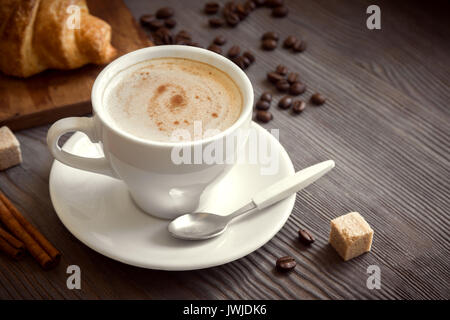 Coffee with croissant for breakfast. Cappuccino coffee and french croissant, tint image. Stock Photo