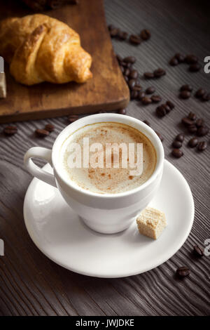 Coffee with croissant for breakfast. Cappuccino coffee and french croissant, tint image. Stock Photo