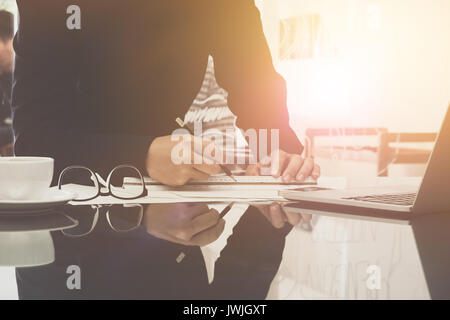 Image of engineer drawing plan on blue print and using laptop computer in office near working site Stock Photo