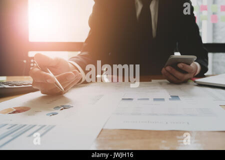 Businessmen are analyzed data from report using smartphone and laptop computer. Stock Photo