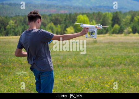 Teenager controling unmanned aerial vehicle (quadrocopter). Boy with quadrocopter drone. Stock Photo