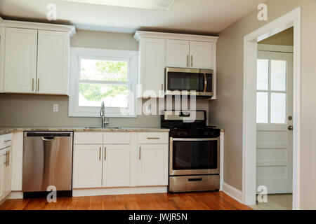 Gourmet kitchen features white shaker cabinets with marble countertops, stone subway tile backsplash, double door stainless steel refrigerator and gor Stock Photo