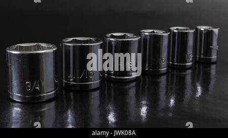 Chrome sockets of diminishing sizes against dark background Stock Photo