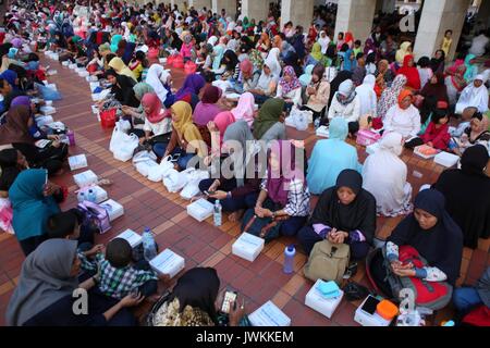 Thousands of Indonesian people break their fast at the Istiqlal Mosque  in Jakarta, Indonesia. Every day during the holy month Ramadan, board of the mosque makes 3,000 servings of food distributed free of charge to the poor people and pilgrims. In Ramadan, Muslims do not eat, drink, or smoke from dawn to sunset. Stock Photo