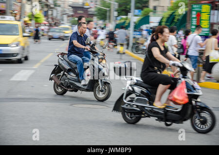 Chinese people riding electric scooters in Shanghai. Stock Photo