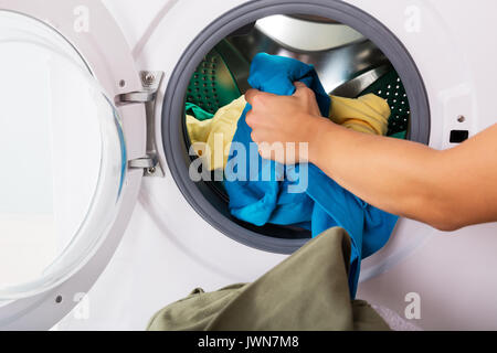 Close-up Of Woman Hand Loading Dirty Clothes In Washing Machine Stock Photo